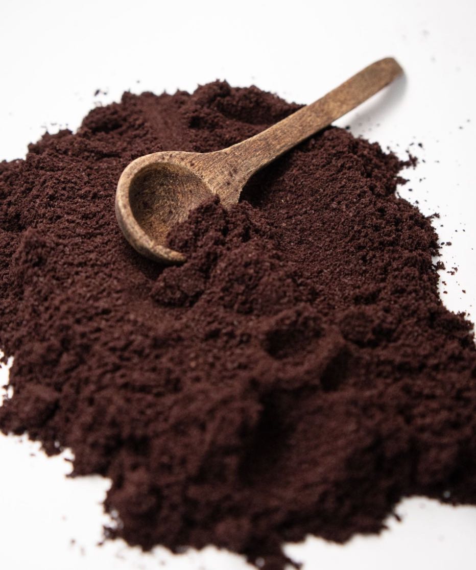 Wooden spoon in a pile of powdered acai on a white background