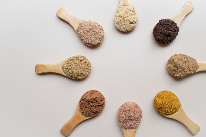 Wooden spoons with various superfoods on a light gray background